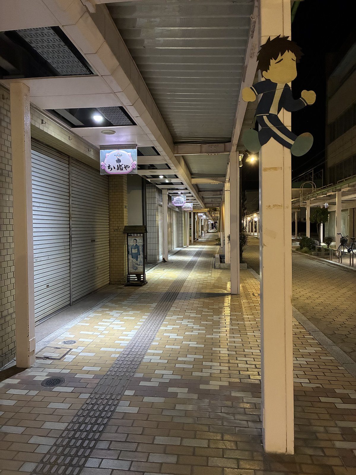 夜の商店街。シャッターが下りていて人の姿はありません