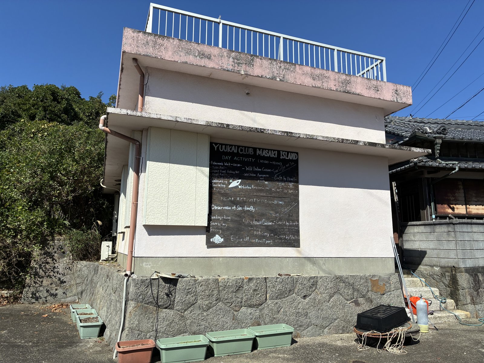 間崎島の建物の壁に掲げられた、YUUKAI CLUB MASAKI ISLANDのアクティビティの黒板