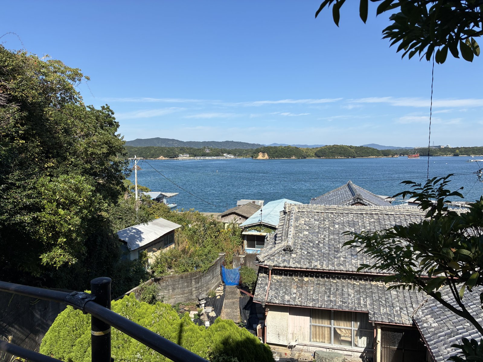 間崎島の集落の瓦屋根と、その向こうの英虞湾