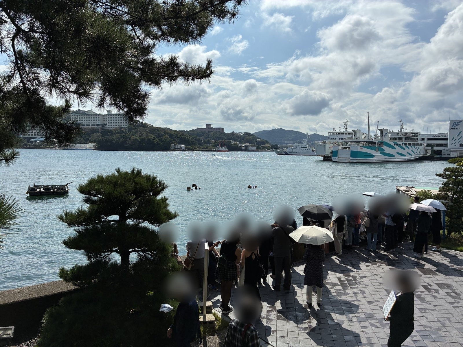 海女の実演を海沿いで見物する人たち