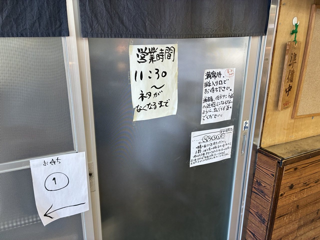 丸八食堂の入口に貼られた営業時間の紙と準備中の札