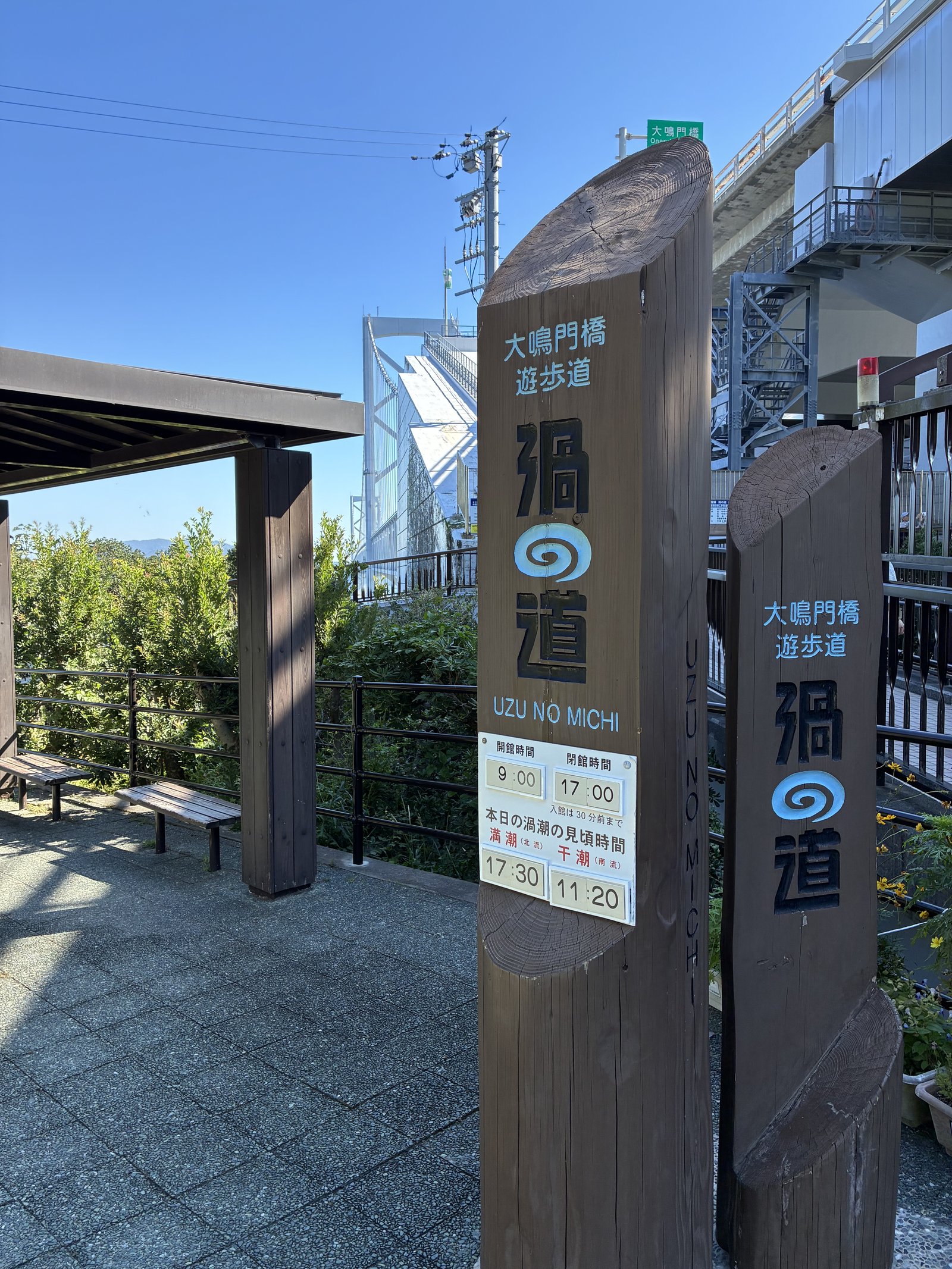 「大鳴門橋遊歩道 渦の道」の木の看板と、入口の前の屋根つきのベンチ